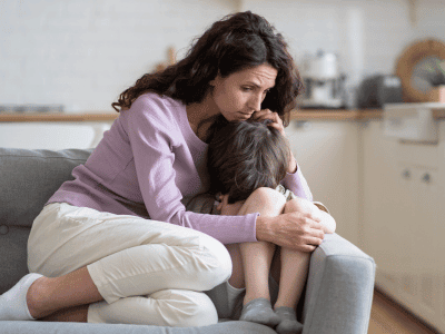 Mother comforting emotional child on sofa